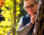 Photo of elderly woman behind a tree in nature