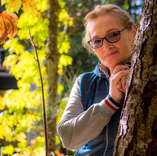 Photo of elderly woman behind a tree in nature