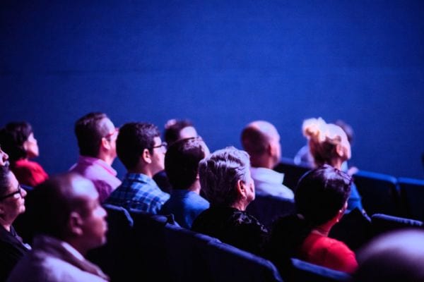 Photo of people seated watching a movie at a movie theater.