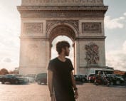 Photo of young man standing in front of Arc de Triomphe in Paris