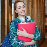 Photo of high school student with headphones, red binder and backpack