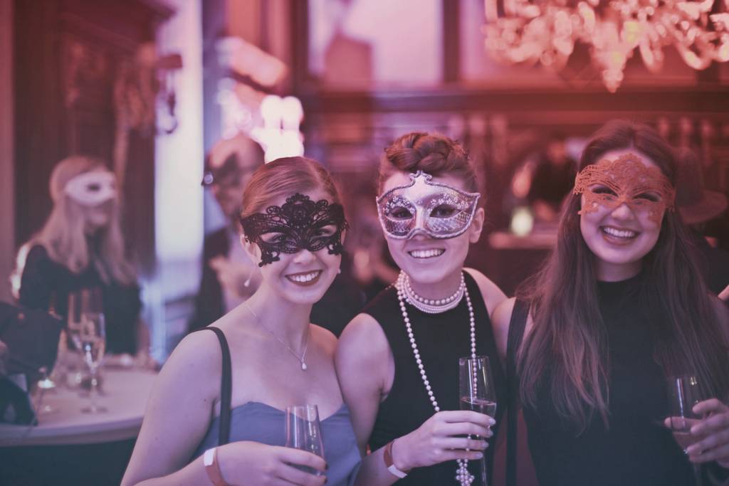 Mardi-Gras Image of three women wearing masks for Mardi Gras at a restaurant